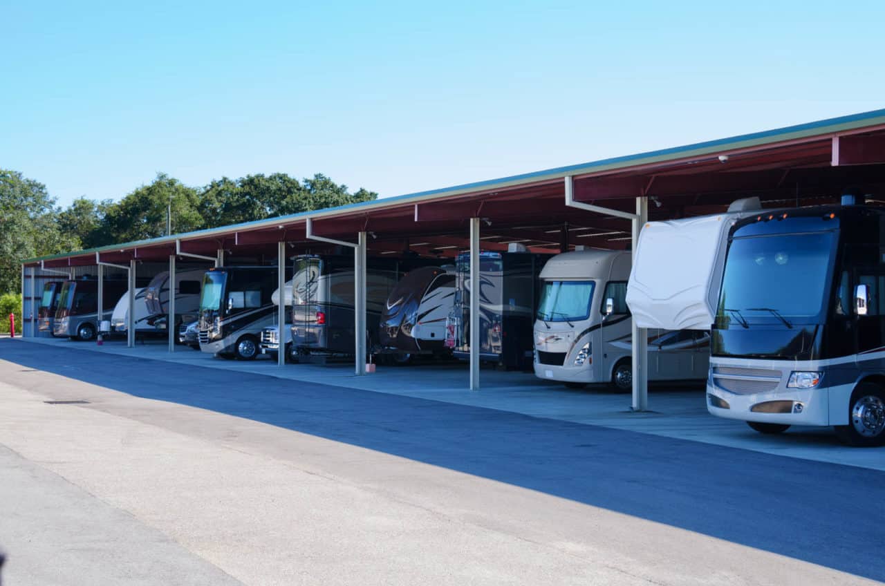 RV recreational vehicle storage parking covered garage filled with many new looking RVs and trailers.